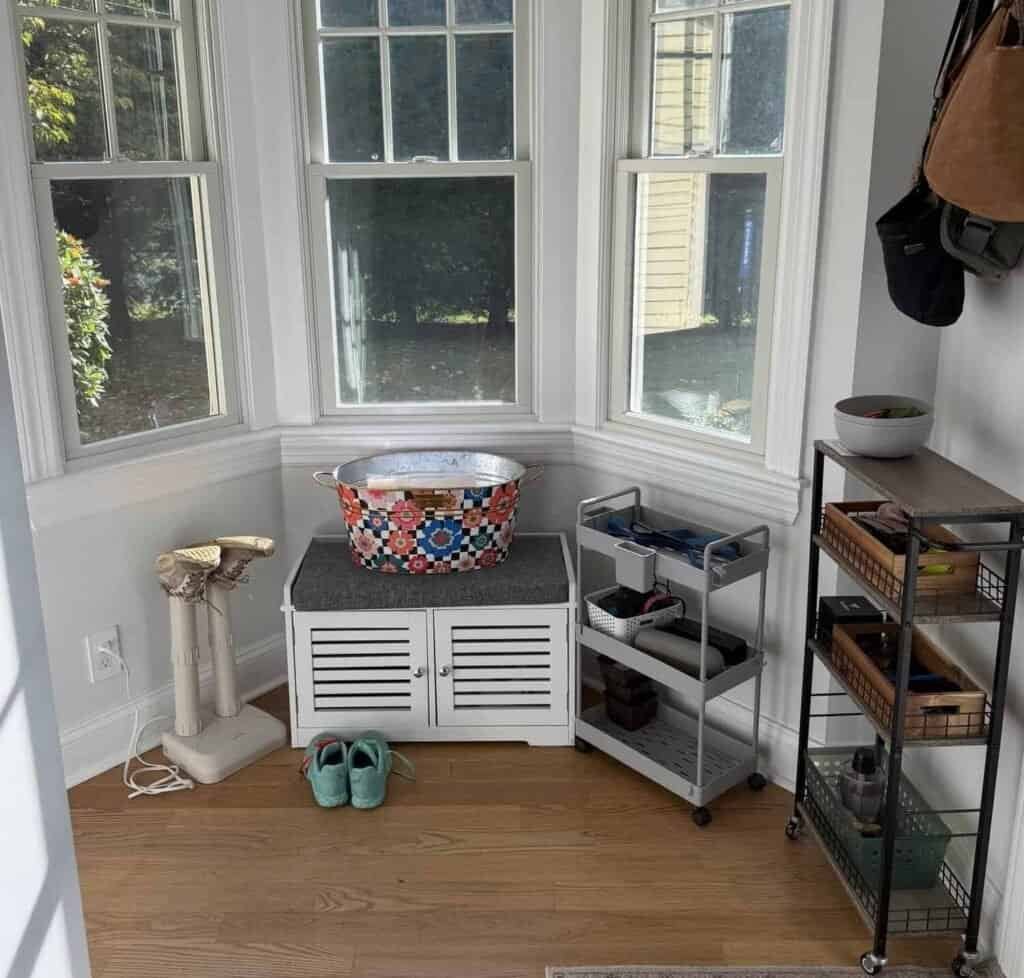 Before: cluttered bay window drop zone with wire shelves, bins, and shoes by the back door