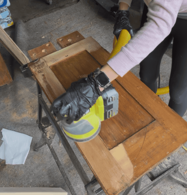Sanding an old Dutch cupboard door with an orbital sander to upcycle it
